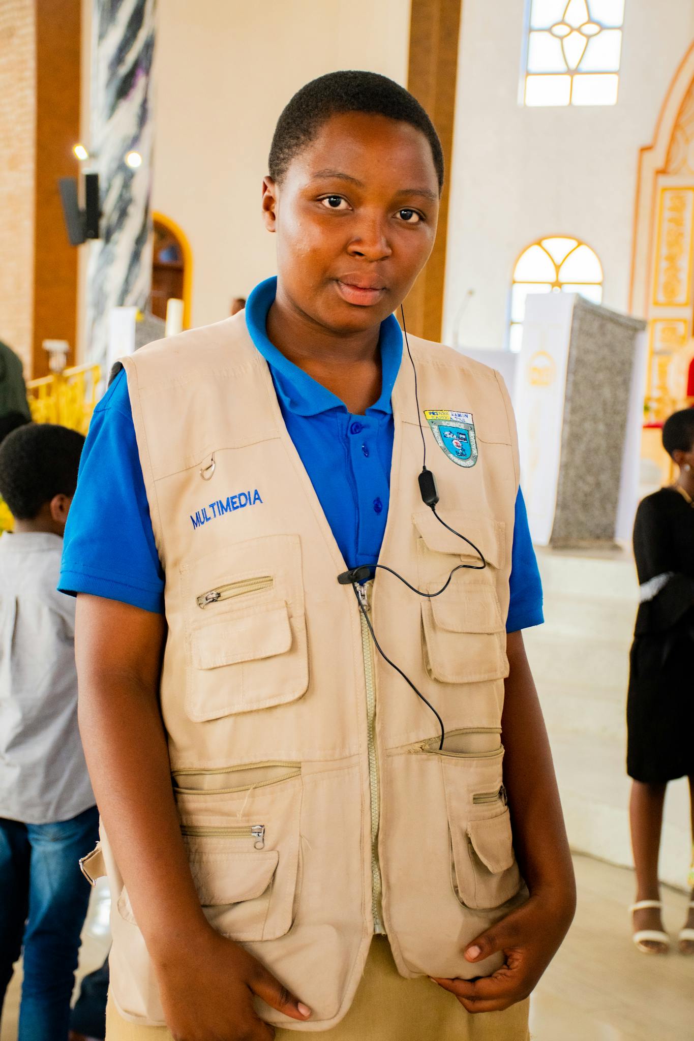 A young multimedia technician wearing a vest in a church interior during daytime.